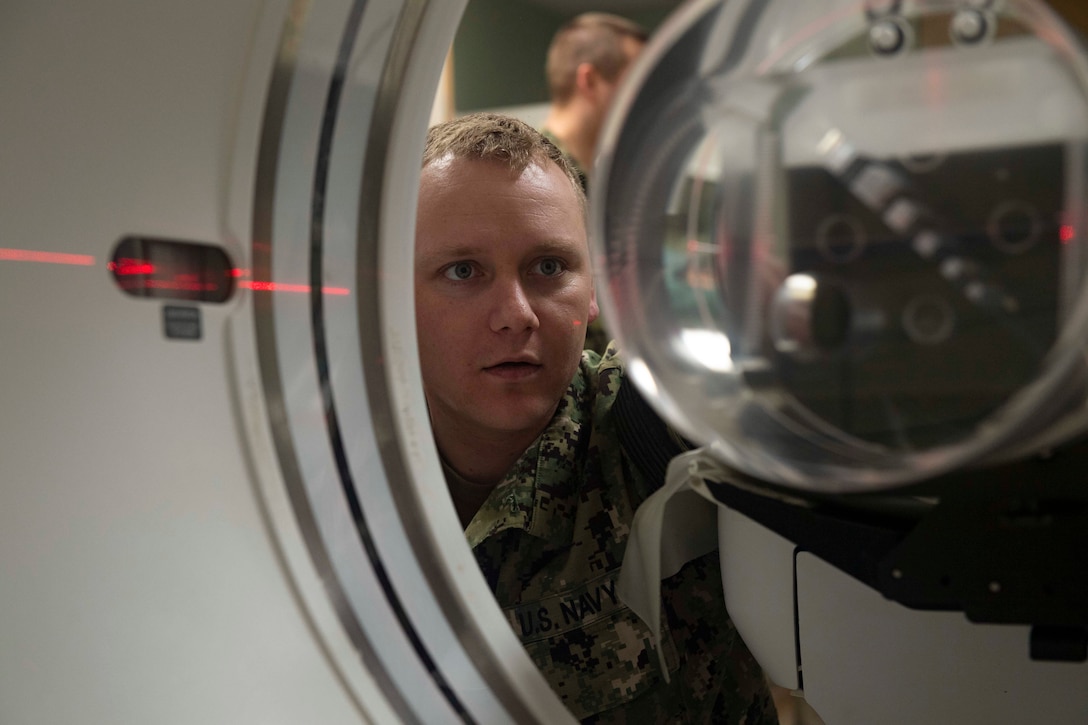 A sailor looks at a CT scan machine.