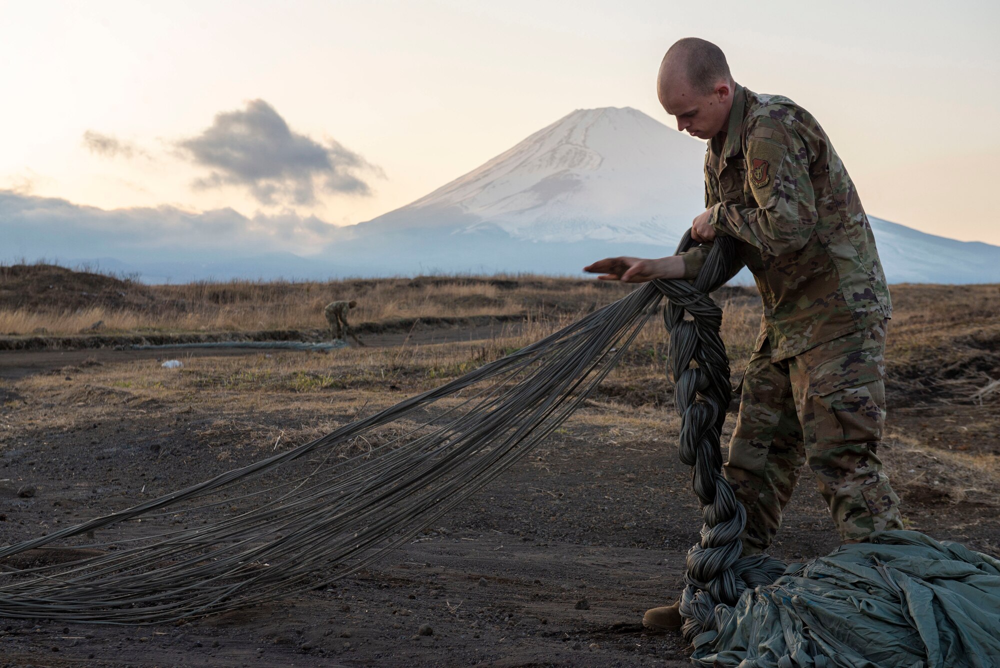 Staff Sgt. Nicholas Adkins, 374th Logistics Readiness Squadron combat mobility flight supervisor, folds parachute suspension lines before stowing the parachute inside a recovery bag