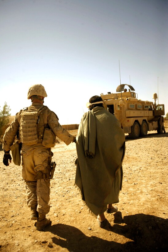 Marine with Combined Anti-Armor Team 1, 1st Battalion, 5th Marine Regiment, escort enemy prisoner of war away for questioning after discovering illegal drugs and improvised explosive device–making material, Helmand Province, Afghanistan, October 19, 2009 (U.S. Marine Corps/John McCall)