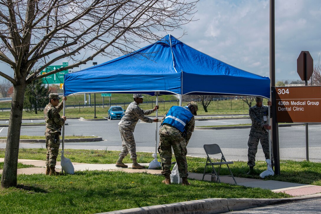 Members from the 436th Medical Group set up a tent in front of the dental clinic at Dover Air Force Base, Delaware, March 30, 2020. Tents were set up for shade at two locations for medical group members that were directing parking for military members, spouses and retirees. Dover AFB medical teams continue to care for Airmen and their families along with state and national response efforts.  (U.S. Air Force photo by Senior Airman Christopher Quail)