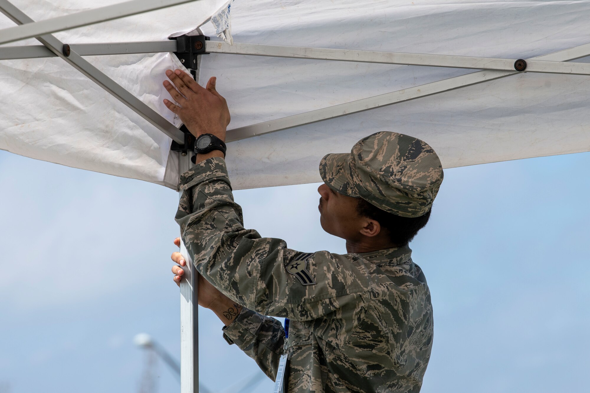Airman 1st Class Christopher Glover, 436th Operational Medical Readiness Squadron dental technician, sets up a tent at Dover Air Force Base, Delaware, March 30, 2020. Tents were set up for shade at two locations for medical group members that were directing parking for military members, spouses and retirees. Dover AFB medical teams continue to care for Airmen and their families along with state and national response efforts. (U.S. Air Force photo by Senior Airman Christopher Quail)