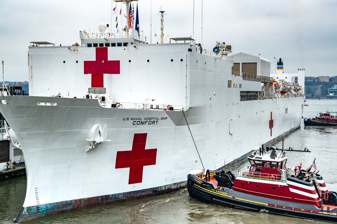 A ship docks with assistance of two boats.