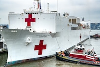 A ship docks with assistance of two boats.