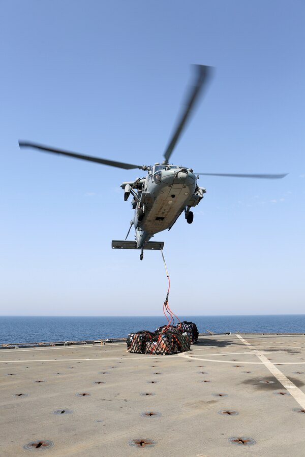 200425-M-CB805-1064 U.S. 5TH FLEET AREA OF OPERATIONS (April 25, 2020) A U.S. Navy MH-60S Sea Hawk assigned to the amphibious assault ship USS Bataan (LHD 5) delivers cargo to the amphibious dock landing ship USS Oak Hill (LSD 51) during a vertical replenishment-at-sea April 25, 2020. Oak Hill, with embarked 26th Marine Expeditionary Unit, is deployed to the U.S. 5th Fleet area of operations in support of naval operations to ensure maritime stability and security in the Central Region, connecting the Mediterranean and Pacific through the Western Indian Ocean and three strategic choke points. (U.S. Marine Corps photo by Staff Sgt. Pablo D. Morrison)