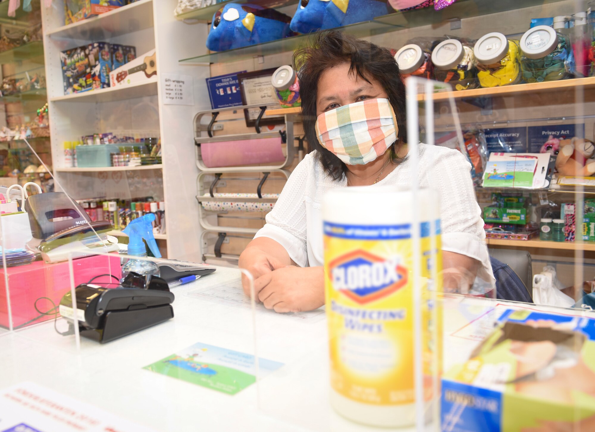 Min Biacan, Army and Air Force Exchange Service cashier, stands behind an acrylic glass shield at the Base Exchange at Ramstein Air Base, Germany, April 21, 2020.