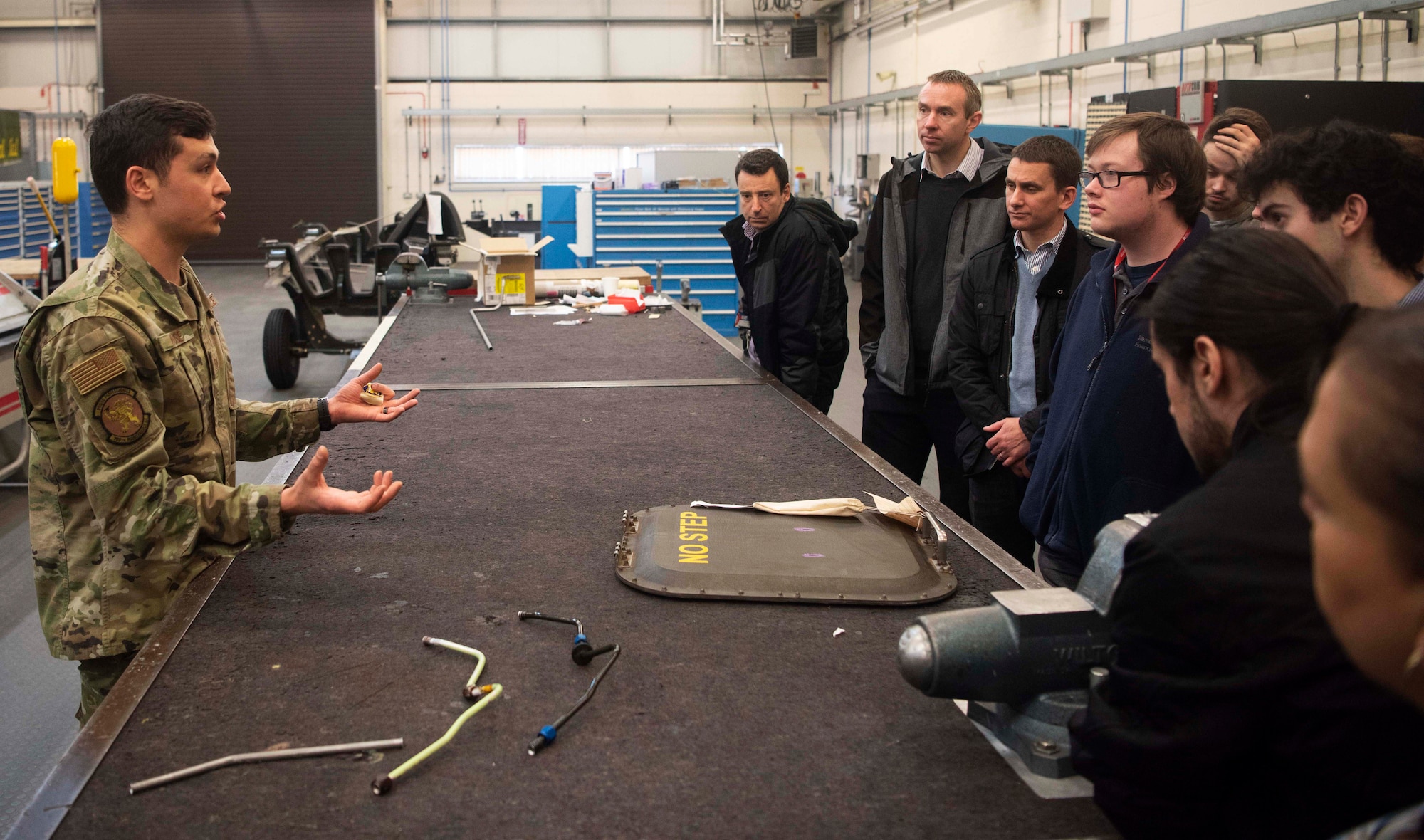 Tech. Sgt. Eric Krause, 100th Maintenance Squadron noncommissioned officer in charge of aircraft structural maintenance, speaks to students from West Suffolk College about a CV-22 carbon fiber composite panel at RAF Mildenhall, England, Feb. 6, 2020. Students toured non-destructive inspection, metals technology and aircraft structural maintenance sections during their visit of the 100th MXS fabrication flight. (U.S. Air Force photo by Airman 1st Class Joseph Barron)