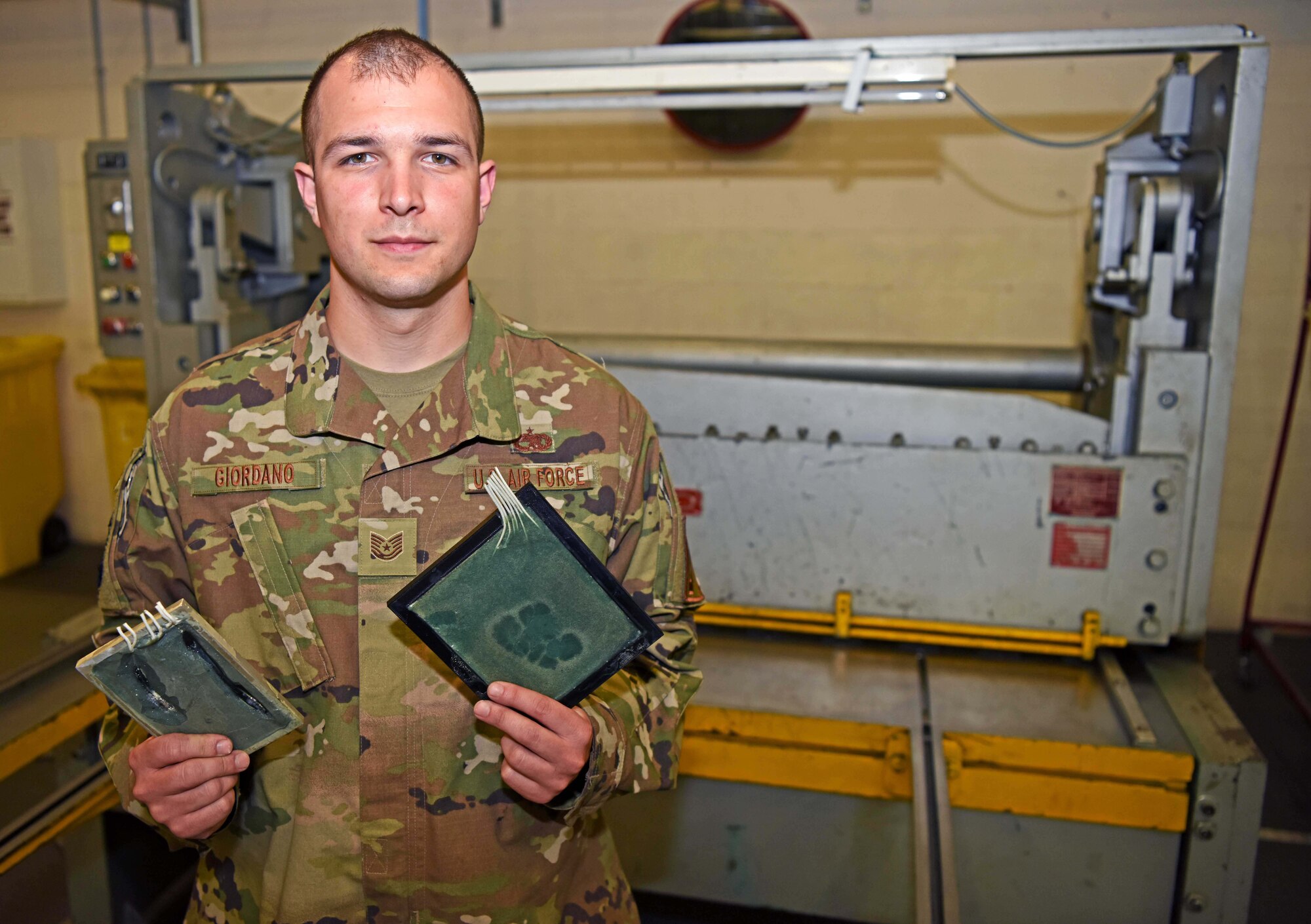 Technical Sergeant Christopher Giordano, 100th Maintenance Squadron aircraft structural maintenance journeyman, poses for photo with a CV-22 Blade Electrical System Trainers at RAF Mildenhall, England, July 26, 2019. Giordano, along with Senior Airman Nick Dickens, 100th MXS metals technology technician, created BEST to mimic a CV-22 blade and electrical system to help Airmen gain additional training and prevent damage to real-world blades. (U.S. Air Force photo by Airman 1st Class Brandon Esau)