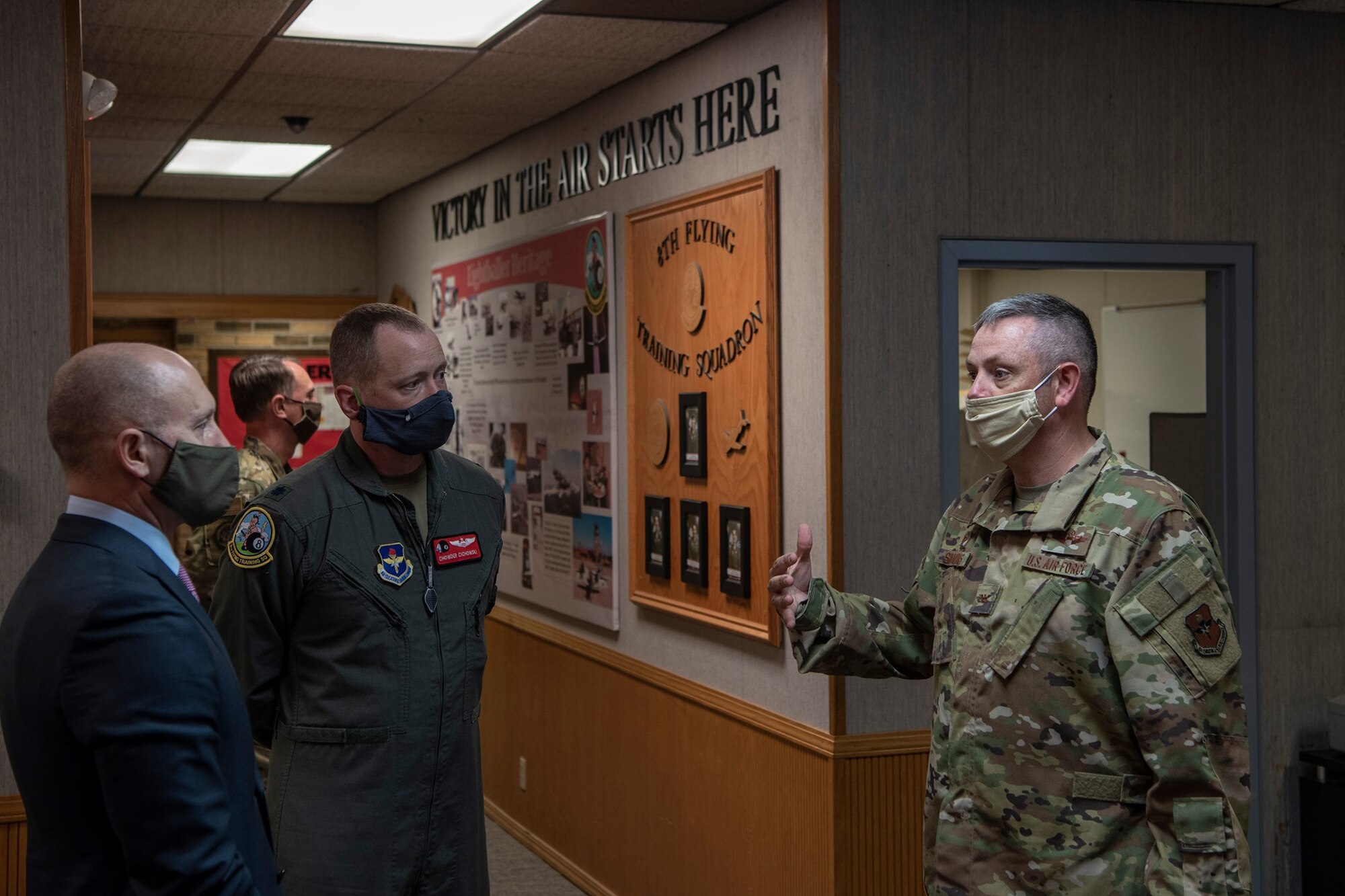 individuals with face masks on standing in flying squadron hallway