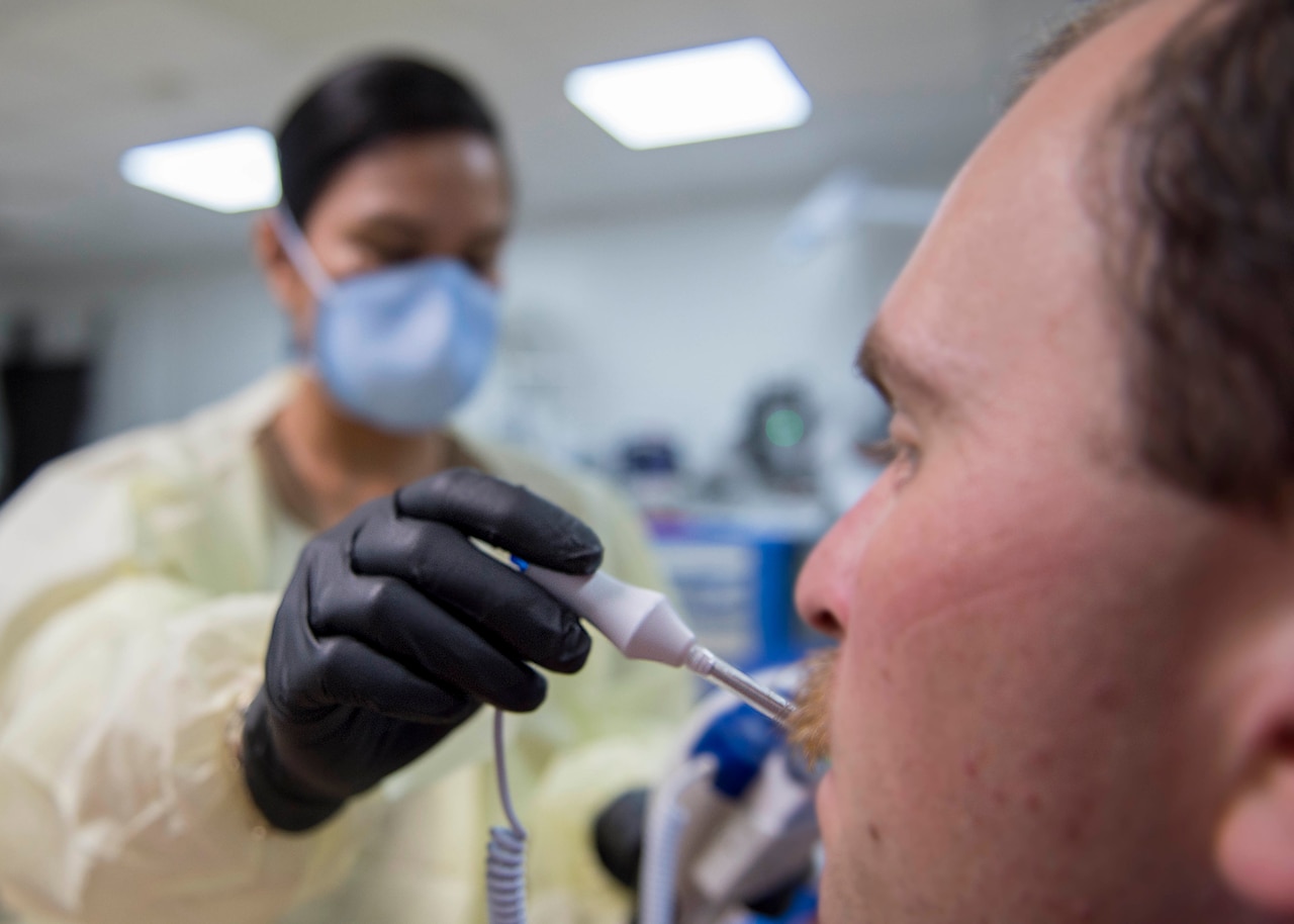 A Navy nurse takes a patient's temperature.