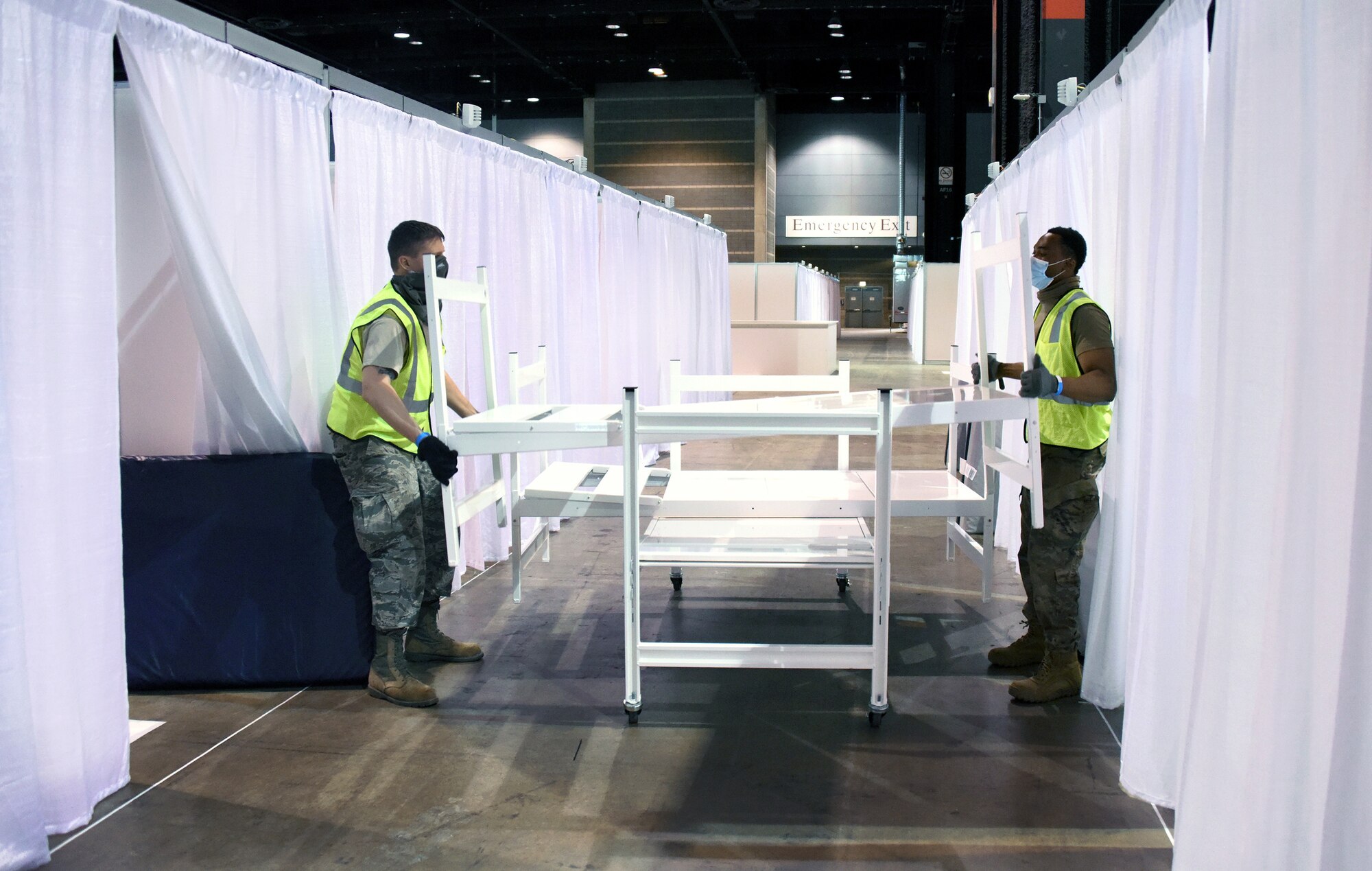 Air Force Tech. Sgt. Adam Dyer, left, and Senior Airman Koami Kunakey, both assigned to the Illinois Air National Guard’s 182nd Airlift Wing, place beds in treatment cubicles at the McCormick Place Convention Center in Chicago while taking part in COVID-19 response efforts, April 11, 2020. Illinois National Guard members were assisted by a nine-person medical team from the Polish military. Since 1993, the Illinois Guard and the Polish military have been partners in the Department of Defense’s State Partnership Program.