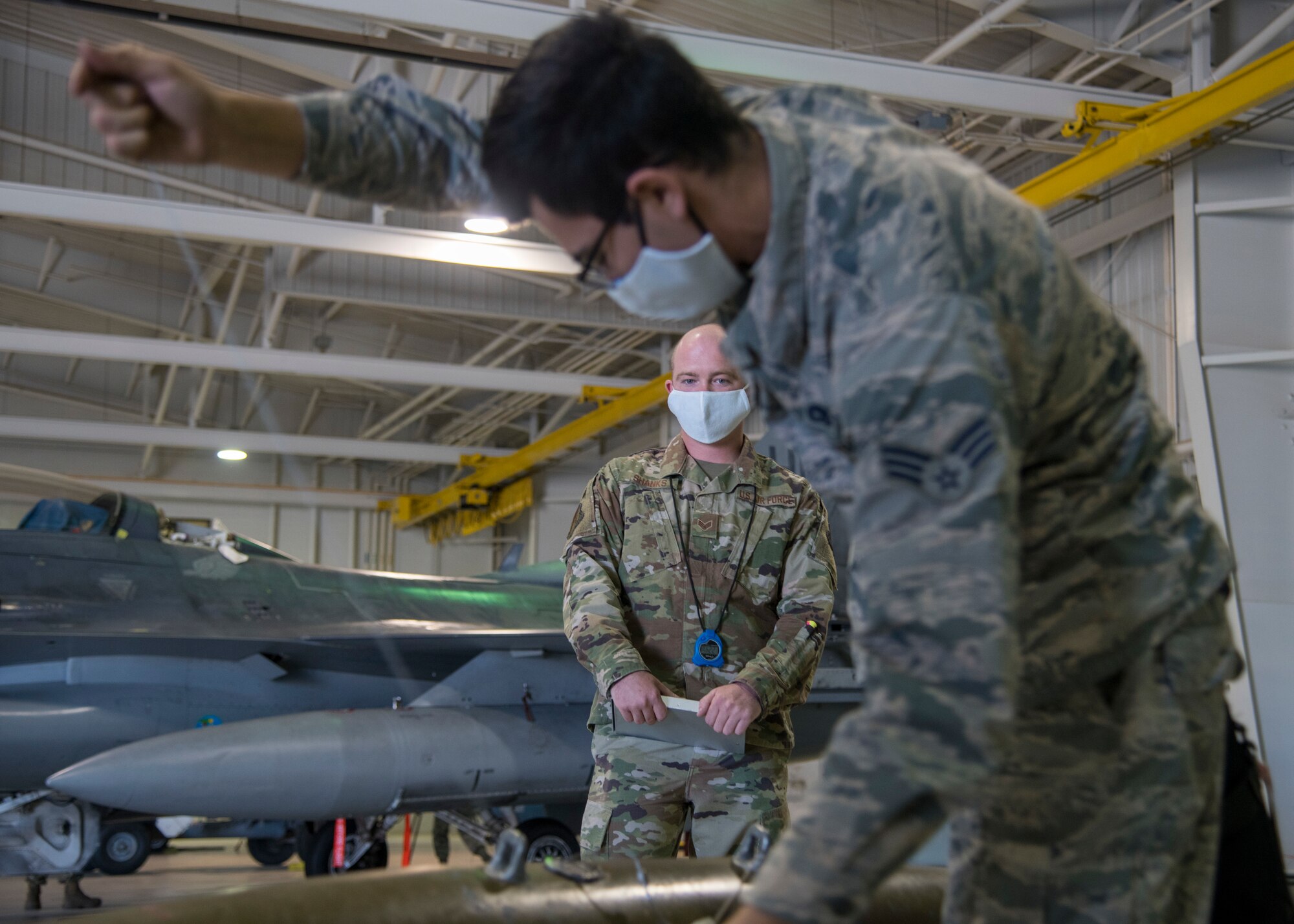 Senior Airman Nathan Shanks, 314th Aircraft Maintenance Unit weapons load crew member, watches a first quarter load competition participant during the event April 28, 2020, at Holloman Air Force Base, N.M. Expert weapons technicians evaluated participants during the competition on items such as safety, munition loading accuracy, tool accountability, and dress and appearance. (U.S. Air Force photo by Senior Airman Collette Brooks)