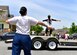 People in workout outfits stand around a trailer outside to perform exercises