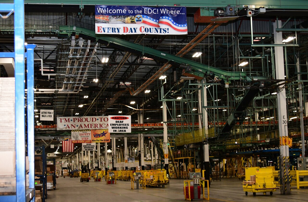 A distribution processing facility has  a line of yellow collection bins in the center of the floor.