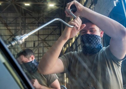 Senior Airman Dennis Powers, right, and Senior Airman Sean McGrath, left, both crew chiefs assigned to the 437th Aircraft Maintenance Squadron, removes a screw while replacing a window on the flightdeck of a C-17 Globemaster III aircraft at Joint Base Charleston, S.C., April 28, 2020. The 437th AMXS is still generating aircraft to support local training flights, missions from Air Mobility Command and supporting training for aeromedical evacuation personnel while being critically manned during the COVID-19 pandemic.The 437th AMXS is also implementing physical distancing when possible and following other Centers for Disease Control guidelines. Additionally, they have trained some of their personnel to decontaminate aircraft before and after missions to keep aircrews and 437th AMXS personnel safe. (U.S. Air Force Photo by Staff Sgt. Megan Munoz)
