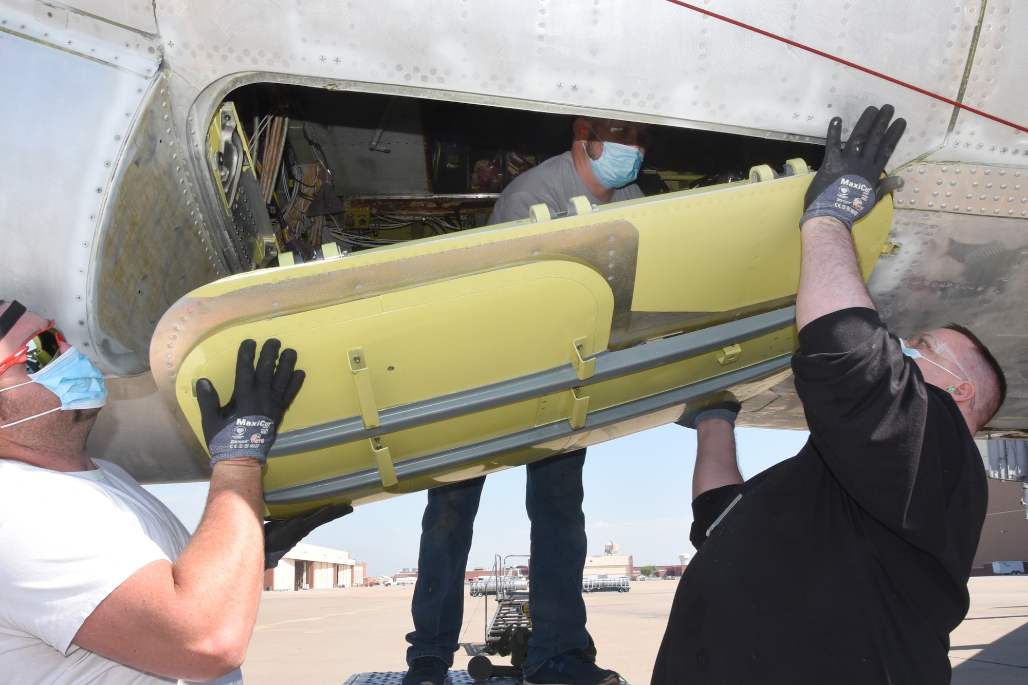 Daniel Geyer, Corey Roundtree and Avrome Sullivan, with the 565th Aircraft Maintenance Squadron, replace the lower hatches on “Wise Guy” as part of programmed depot maintenance. “Wise Guy” is the second B-52 Stratofortress to be regenerated for service. (U.S. Air Force photo/Kelly White)