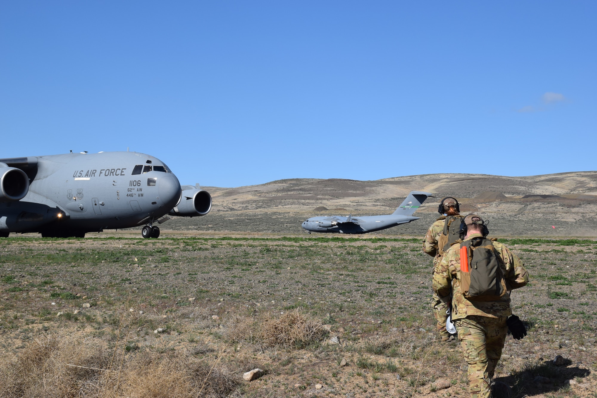 Tech. Sgt. Rachel Andrew, 8th Airlift Squadron loadmaster, and Tech. Sgt. Justin Hampton, 16th Airlift Squadron loadmaster, both students in the Advanced Instructor Course, return to C-17 Globemaster IIIs after participating in an aeromedical evacuation exercise at Yakima Training Center, Wash., April 23, 2020. Enlisted students in the Advanced Instructor Course and pilots in the C-17 Weapons Instructor Course frequently train together for common learning objectives. (Courtesy Photo)