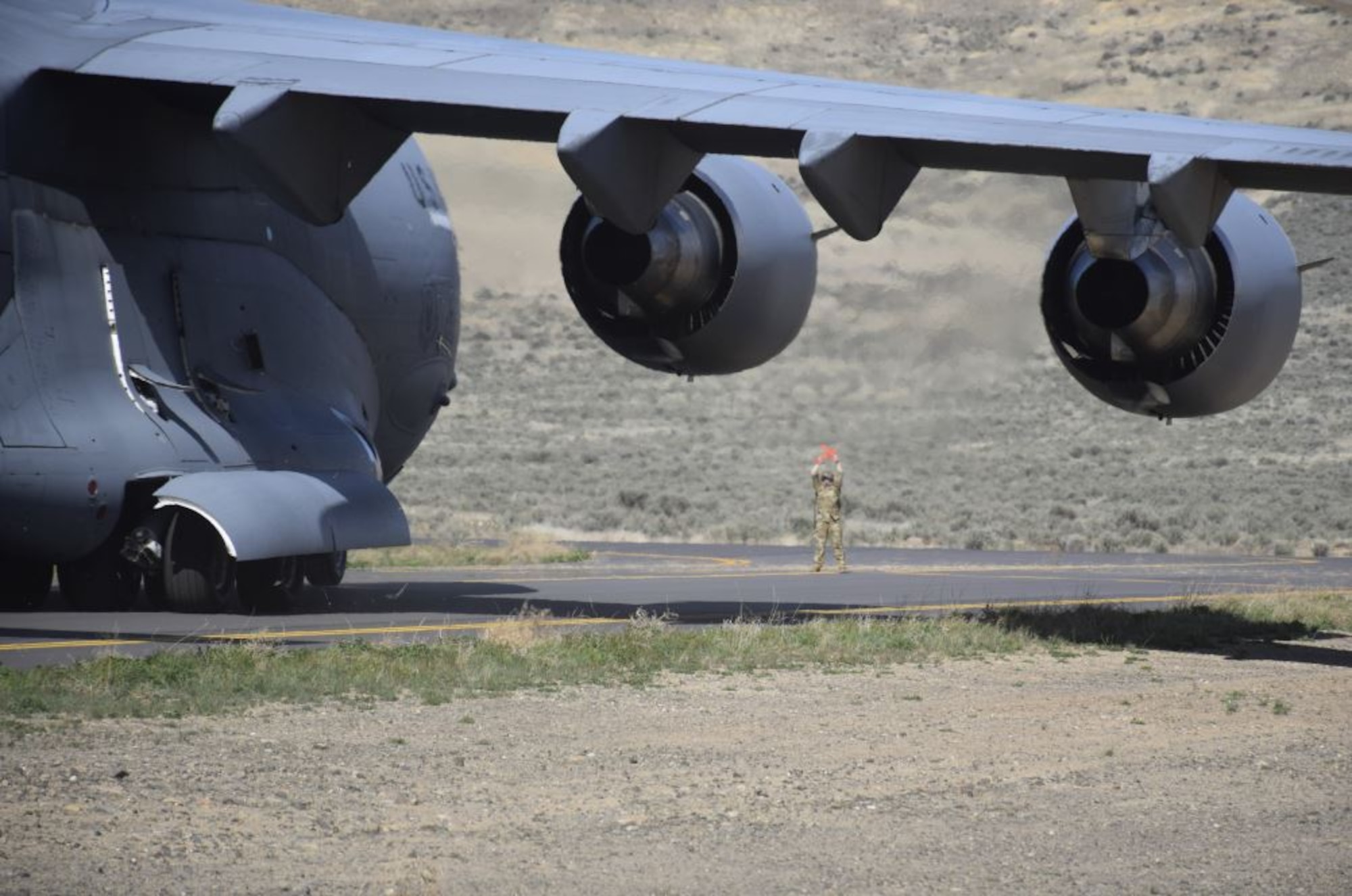 Tech. Sgt. Rachel Andrew, 8th Airlift Squadron loadmaster and Advanced Instructor Course student, marshals a C-17 Globemaster III on the Mettie Airstrip at Yakima Training Center, Washington, April 23, 2020. The AIC, taught out of the 57th Weapons Squadron at Joint Base Lewis-McChord, Wash., produces highly trained aircrew members in weapons systems across the U.S. Air Force and Defense Department. (Courtesy Photo)