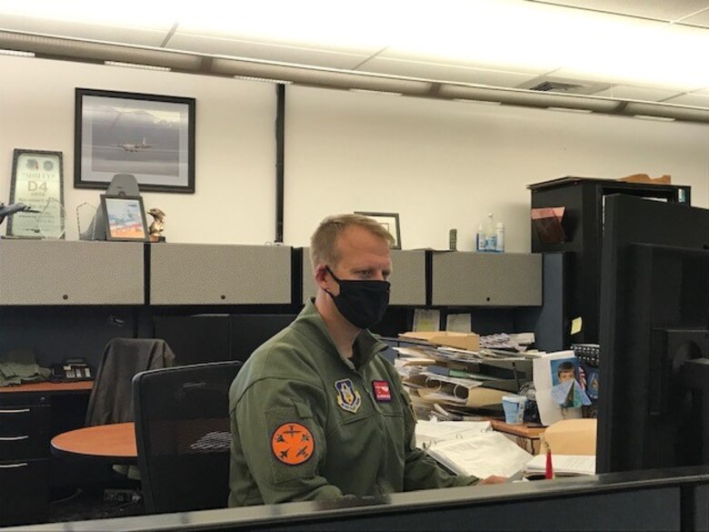 Maj. Jonathan Shiflett sitting at his computer desk wearing a face covering.