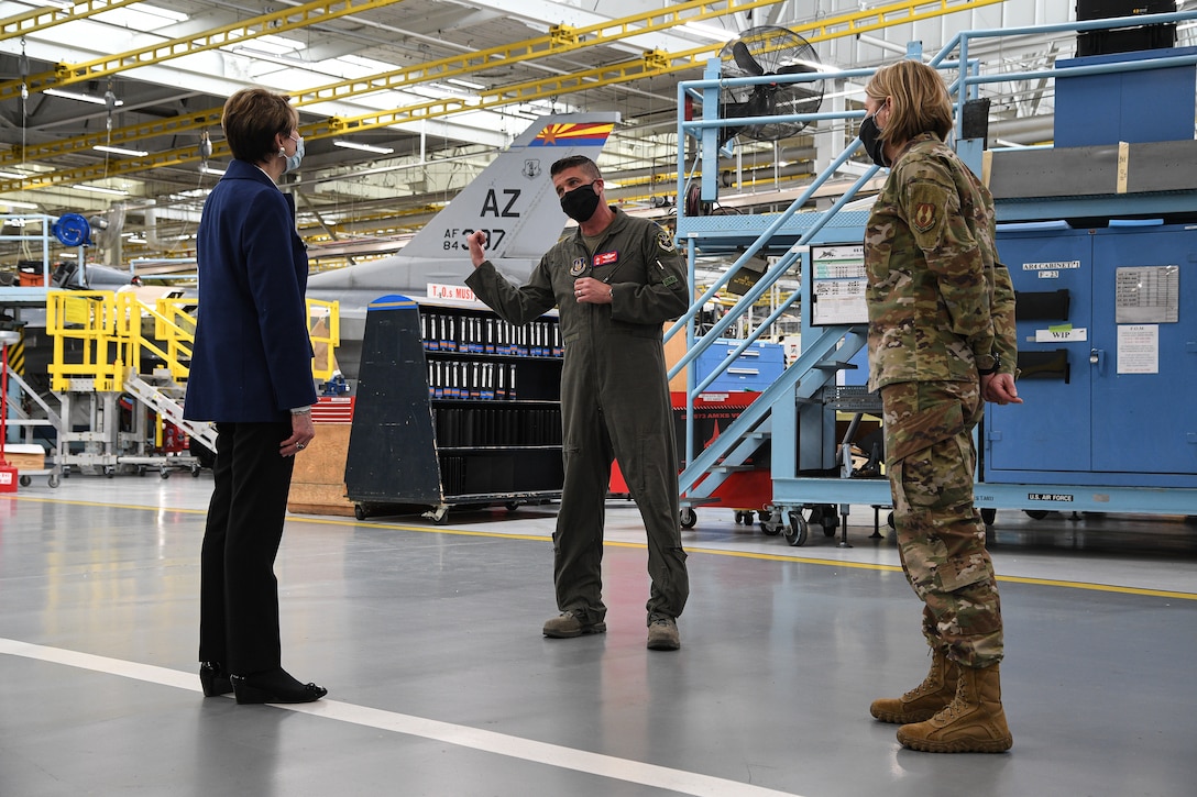 Secretary of the Air Force Barbara Barrett listens to Lt. Col. Nathan Litz, 514th Flight Test Squadron, inside a depot maintenance hangar.