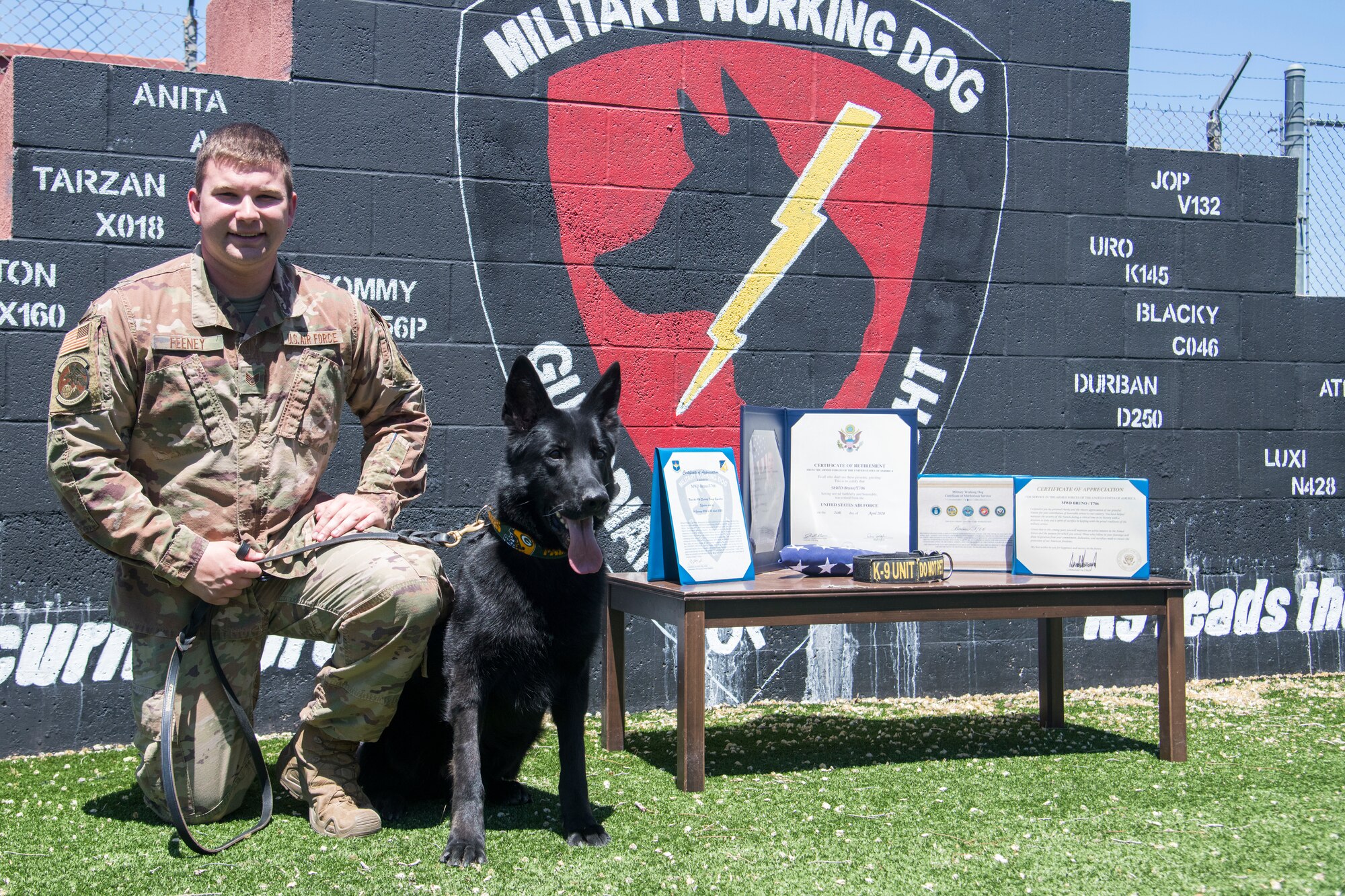 Staff Sgt. Chase Feeney, 49th SFS military working dog handler and MWD Bruno, 49th Security Forces Squadron explosive detector dog, pose for a photo prior to MWD Bruno’s retirement ceremony, April 24, 2020, on Holloman Air Force Base, N.M. Not only did MWD Bruno train in obedience and explosive detection here for the last year and a half with his handler, Feeney, MWD Bruno deployed twice to Al-Udied, Qatar, and once to Al-Jaber, Kuwait with Feeney. (U.S. Air Force photo by Senior Airman Collette Brooks)