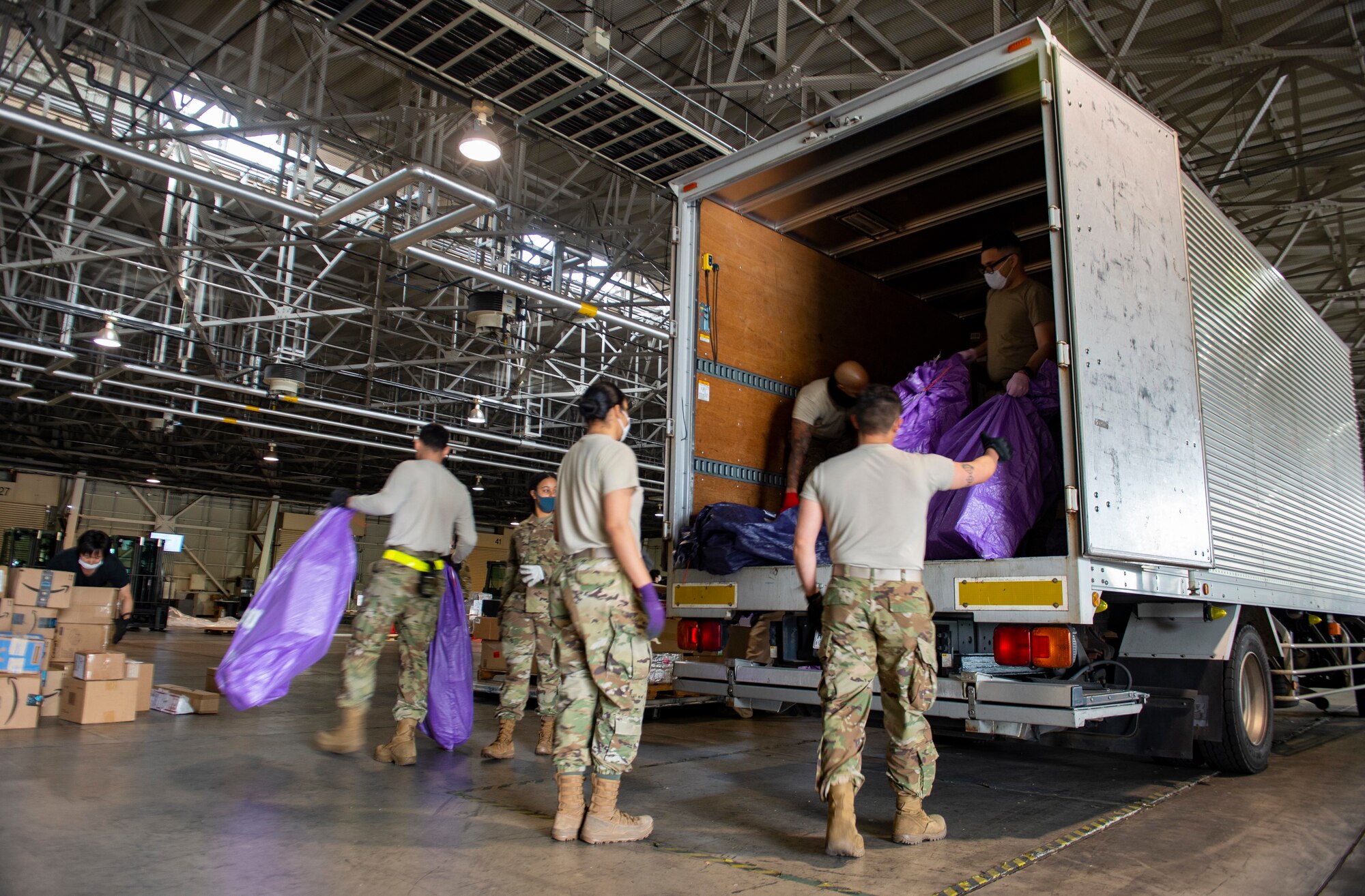 Airmen with the 730th Air Mobility Squadron, the 36th Airlift Squadron and Pacific Air Forces Air Postal Squadron work together to build pallets of processed mail at Yokota Air Base, Japan, April 17, 2020. Due to COVID-19, planes that would normally take the mail bound for Misawa Air Base, Japan, from Haneda or Narita Airport, have been reduced to one flight per day, requiring the mail to be processed and flown through Yokota. (U.S. Air Force photo by Senior Airman Gabrielle Spalding)