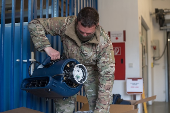 An Airman lifts an ion distribution unit out of a box.