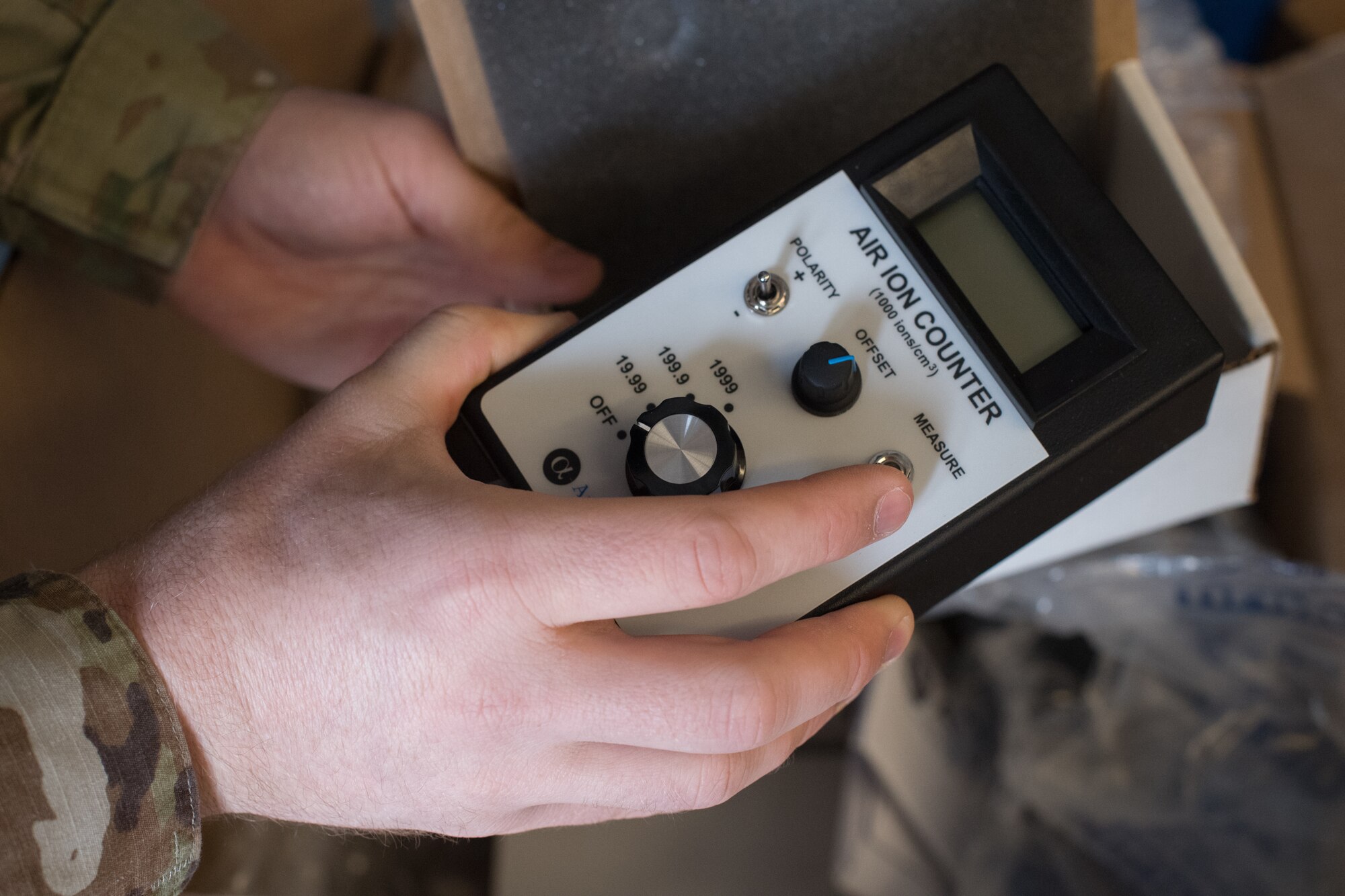 Two hands holding an ion counting device.