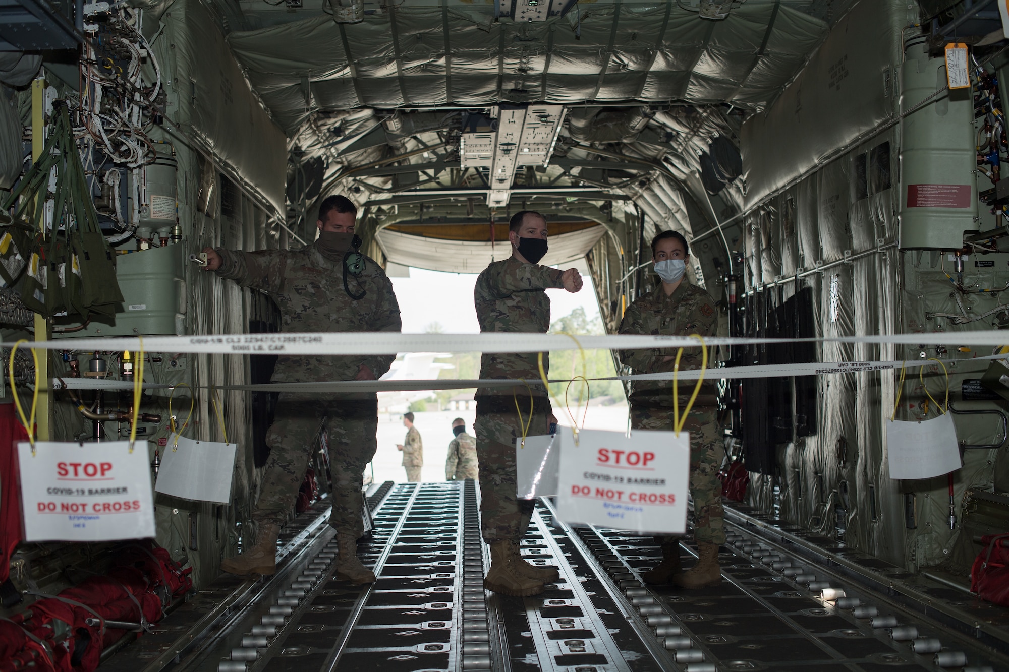 Three Airmen standing aboard an aircraft.