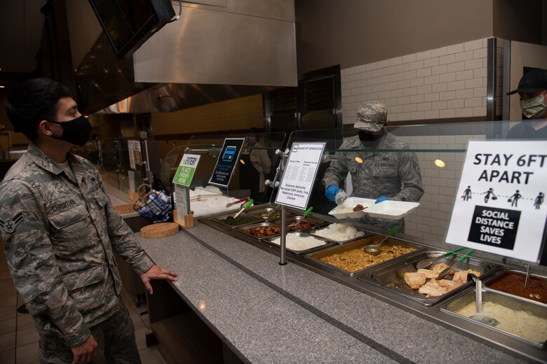 U.S. Air Force Airman 1st Class Jacob Christian, left, 860th Aircraft Maintenance Squadron C-17 Globemaster III crew chief, waits for his food as Senior Airman Marlon Payumo, 60th Force Support Squadron fitness specialist, scoops rice into a to-go box during the lunch service at the Monarch Dining Facility April 24, 2020, at Travis Air Force Base, California. The Monarch is offering to-go meals to service members only due to the coronavirus pandemic. (U.S. Air Force photo by Tech. Sgt. James Hodgman)
