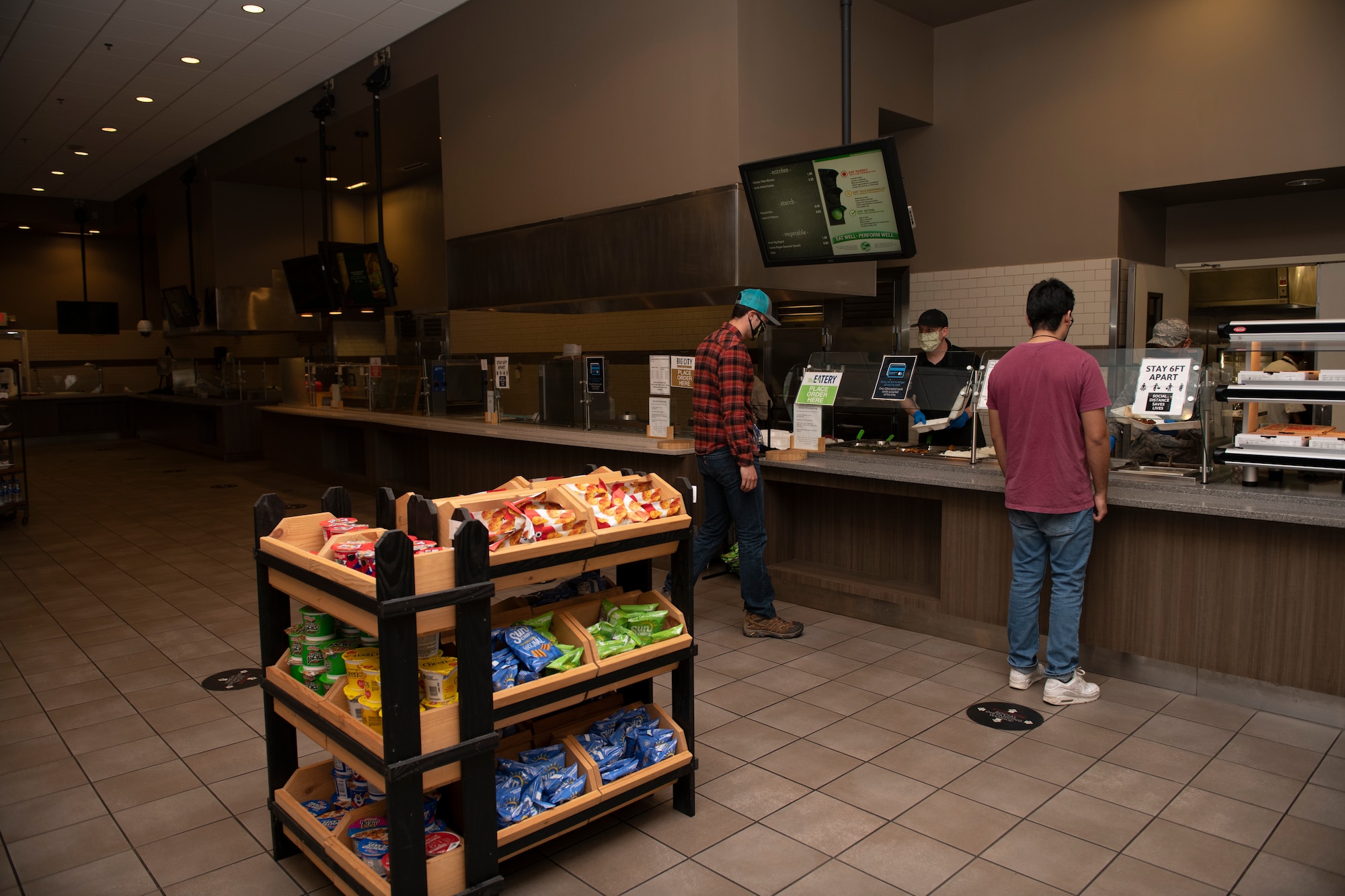 U.S. Airmen place their lunch orders inside the Monarch Dining Facility April 24, 2020, at Travis Air Force Base, California. The Monarch is offering to-go meals to service members only due to the coronavirus pandemic. The facility is available to service members on and off duty. (U.S. Air Force photo by Tech. Sgt. James Hodgman)