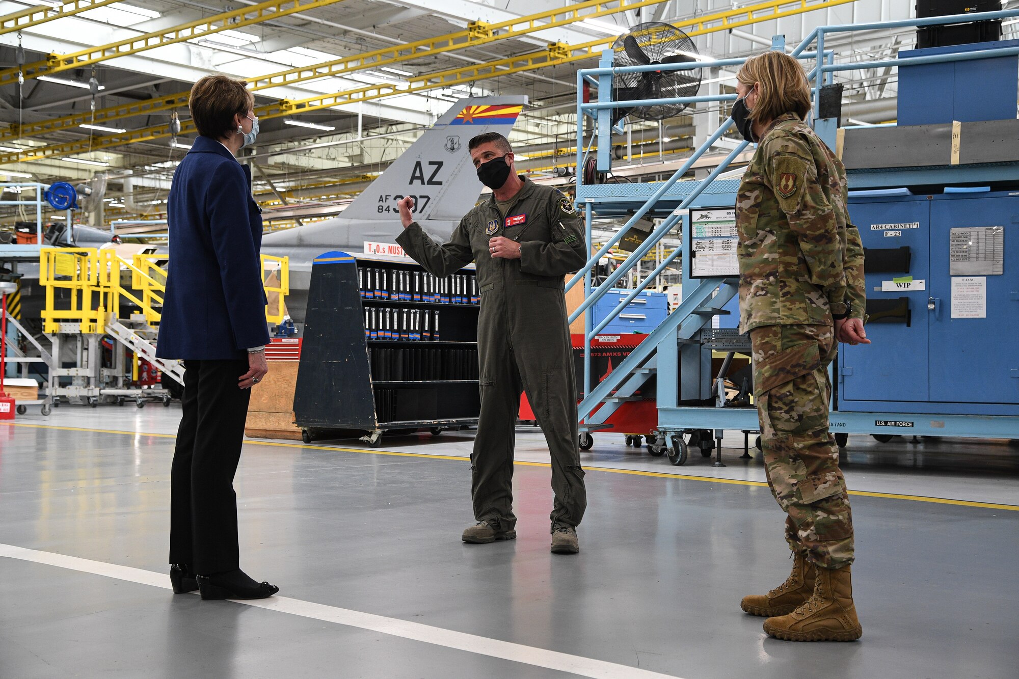 Secretary of the Air Force Barbara Barrett listens to Lt. Col. Nathan Litz, 514th Flight Test Squadron, inside a depot maintenance hangar.