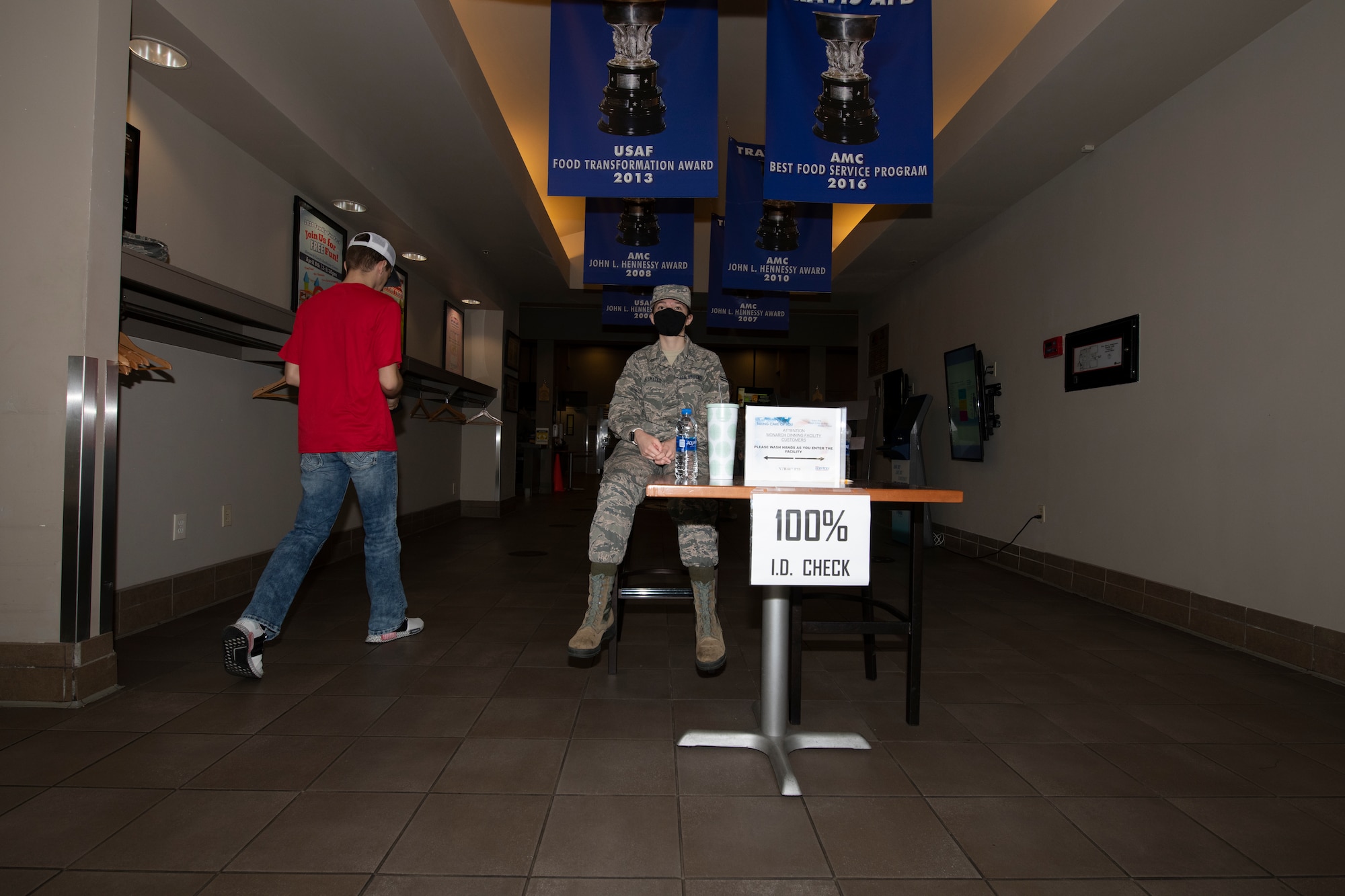 U.S. Air Force Airman 1st Class Layla Delamater, 60th Force Support Squadron food services apprentice, monitors entry into the Monarch Dining Facility April 24, 2020, at Travis Air Force Base, California. The facility is now only open to service members and requires patrons to wear masks and remain at least six feet apart while inside. (U.S. Air Force photo by Tech. Sgt. James Hodgman)