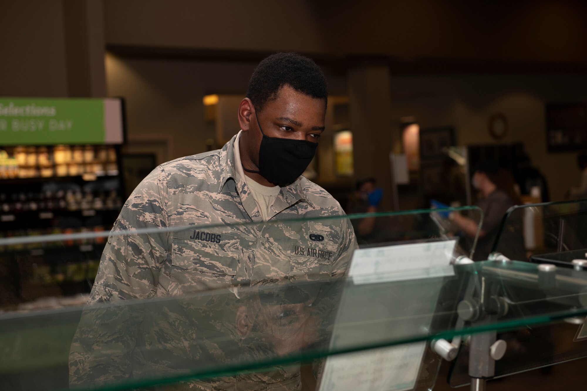 Airman 1st Class Cordell Jacobs, 60th Maintenance Squadron aircraft fuel systems journeyman, waits for his food inside the Monarch Dining Facility April 24, 2020, at Travis Air Force Base, California. The Monarch has implemented procedures to prevent the spread of the coronavirus including restricting access to service members only and requiring all patrons to wear masks. (U.S. Air Force photo by Tech. Sgt. James Hodgman)