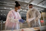 Oklahoma Army National Guard Sgt. Aaron Moore (right), a combat medic/healthcare specialist with Detachment 1, Headquarters Company, 120th Engineer Battalion, 90th Troop Command, matches paperwork to a test sample with a nurse from the Oklahoma City County Health Department.