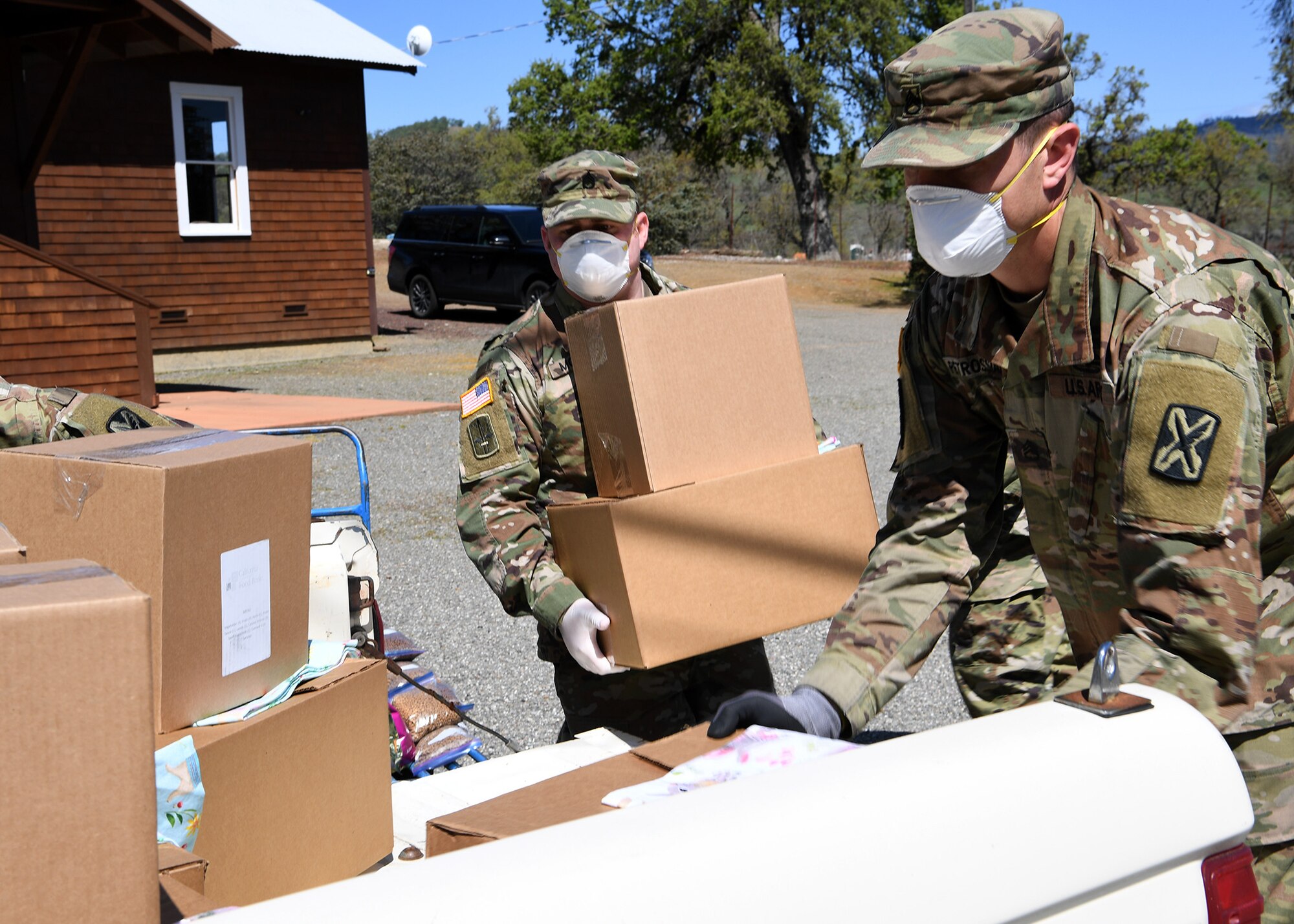 U.S. Army Staff Sgt. Joshua A. Mosley, left, and Staff Sgt. Chris Petrossian, both of the California Army National Guard’s 115th Regional Support Group, load food items into a volunteer’s truck to distribute to Napa Valley residents who are homebound during the COVID-19 crisis while working at Pope Valley Farm Center in St. Helena, California, April 1, 2020.