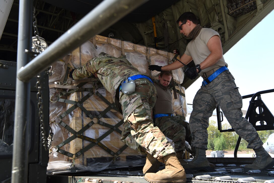 U.S. Airmen assigned to the 721st Aerial Port Squadron push cargo onto a C-130J Super Hercules aircraft.