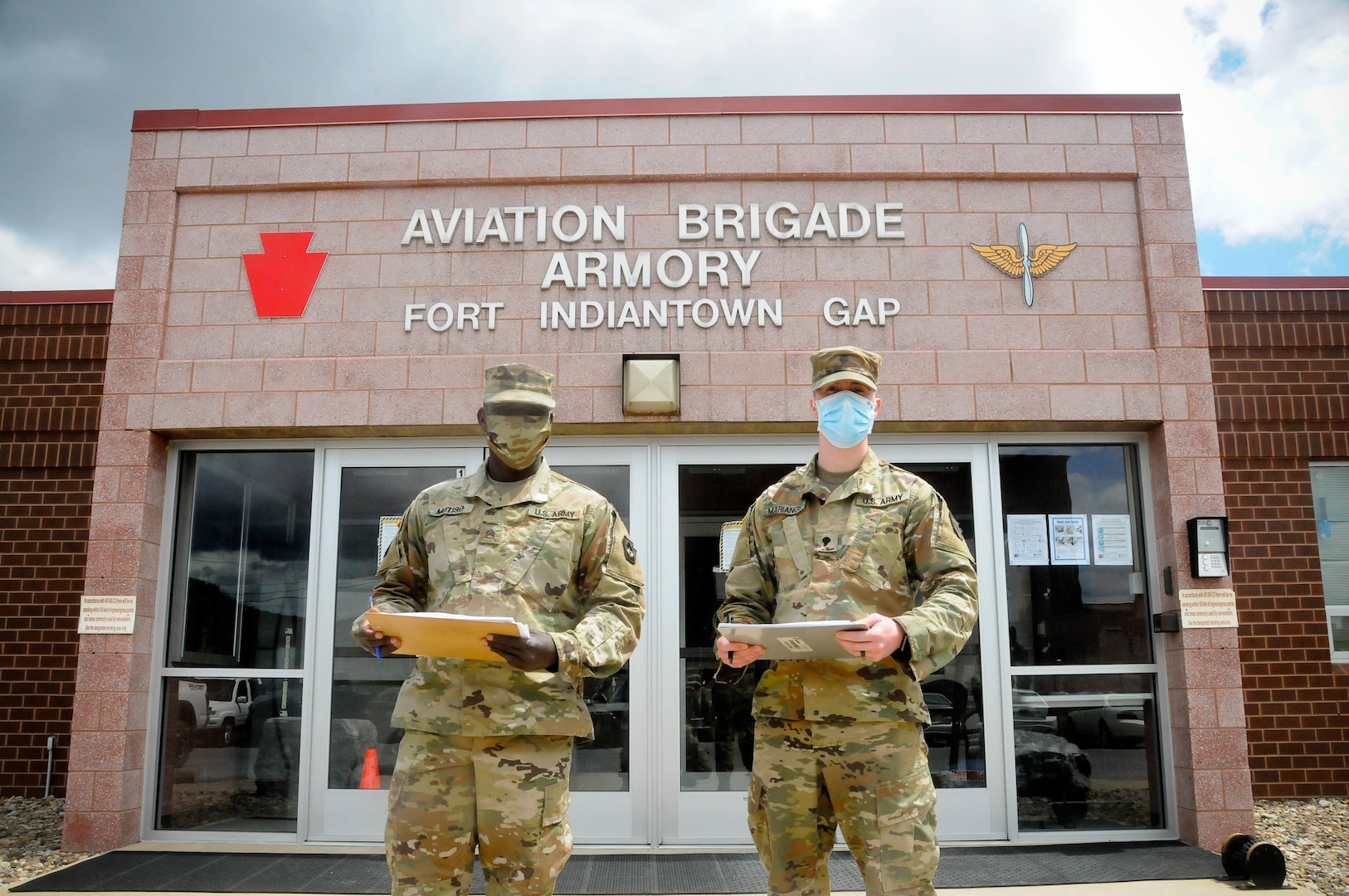 Staff Sgt. Raymond Mutiso, left, a combat medic with the 108th Area Medical Support Company, 213th Regional Support Group, and Spc. Padric Marianos, a construction engineer with the PAARNG Training Center, outside the 28th ECAB Armory. The 28th ECAB is to deploy soon and must gather for training. Soldiers like Mutiso and Marianos screen 28th ECAB Soldiers to prevent the spread of COVID-19 in the formation.