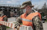 Spc. Taylor Lenhart, a military police Soldier with the 186th Military Police Company, Iowa Army National Guard, helps move a traffic barrier in Des Moines April 27, 2020. Lenhart is one of 60 military police Soldiers supporting the first drive-through COVID-19 testing site in Iowa. Before duty, Lenhart helps her community as a karate instructor by providing virtual classes.