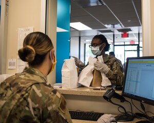 U.S. Air Force Airman 1st Class Kayla Billings, 633rd Dental Squadron dental assistant, gathers prescriptions to take to a patient at Joint Base Langley-Eustis, Virginia, April 28, 2020.  To help expedite the process of acquiring your prescriptions from the Satellite Pharmacy technicians, members from organizations such as pediatrics and the dental squadron help the pharmacy as runners, greeting patients outside of the facility to gather information and deliver prescriptions. (U.S. Air Force photo by Airman 1st Class Marcus M. Bullock)