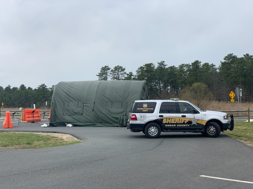 A sheriff's vehicle parked near a military tent.