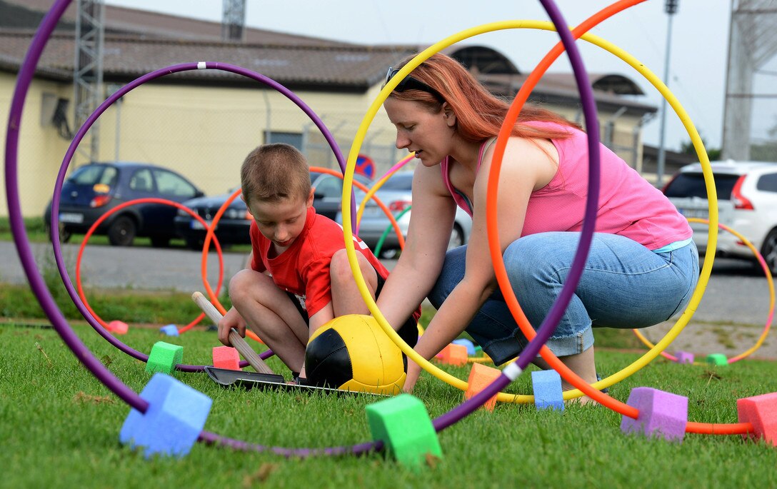 Mom and son manipulate outdoor play equipment