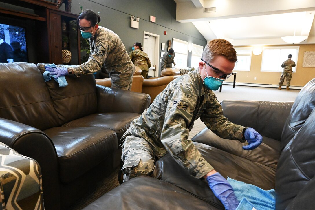 Two soldiers wipe down furniture with sanitizing material at a living memory care facility in Fargo, N.D.