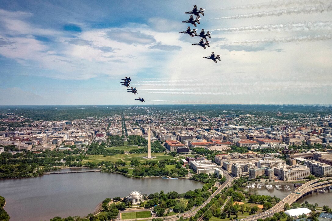 Two formations of jets fly over the Washington Monument and its surroundings.