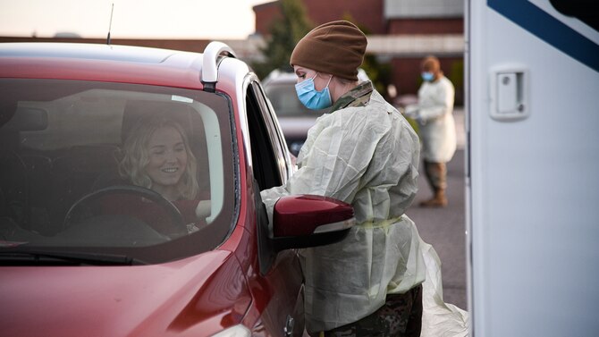 Senior Airman Amber Sansevieri, 75th Medical Group, interacts with a visitor during a drive-thru COVID-19 screening.