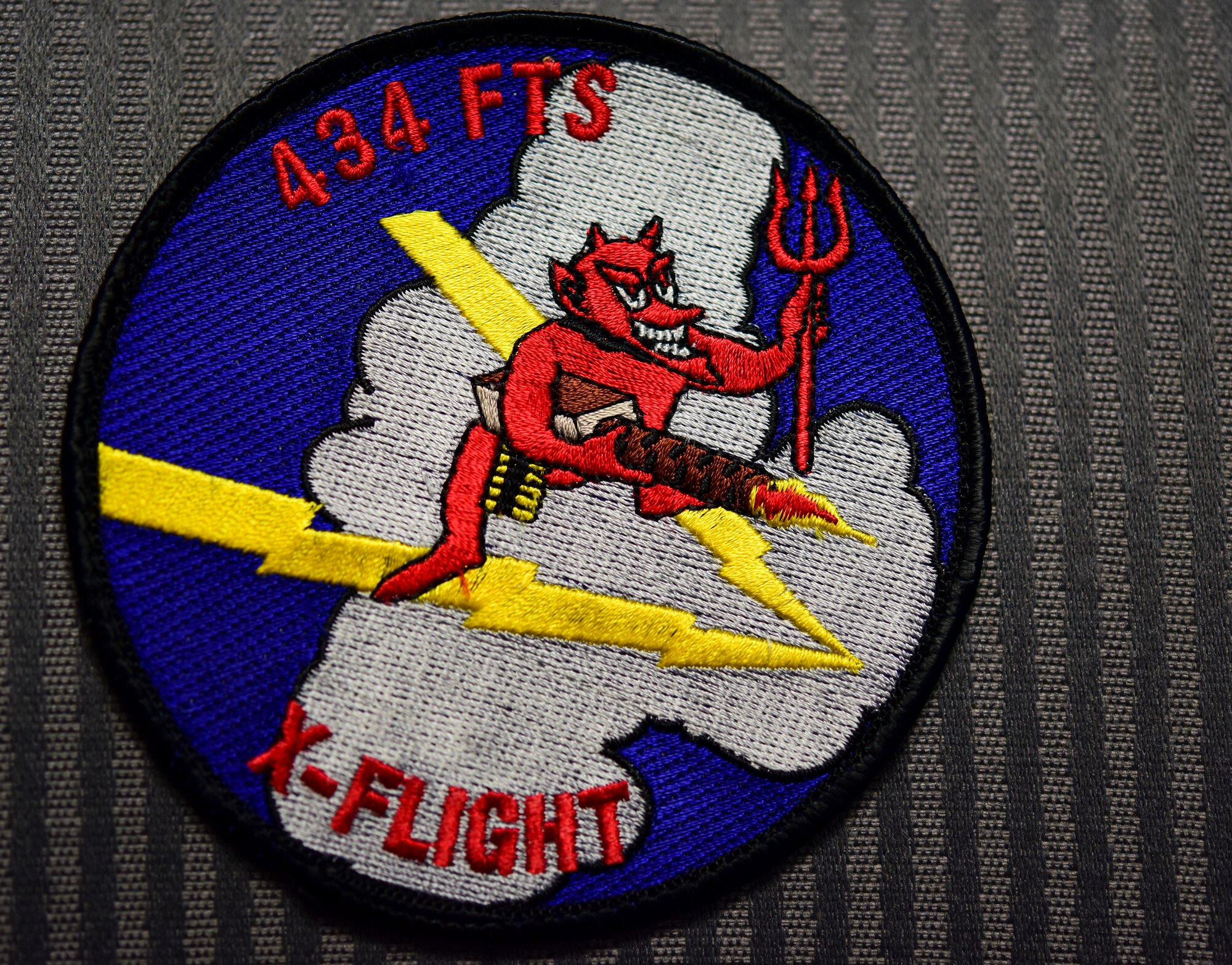 An X flight, also known as Lightning flight, of the 434th Flying Training Squadron at Laughlin Air Force Base, Texas, patch rests on the back of a chair in the flight commander’s office. As a flight commander, Capt. Joshua White, 434th FTS instructor pilot, is among the first echelons responsible for safely and efficiently scheduling people, the mission, and aircraft. His job is to keep the flight pointed in the right direction and enable his instructor pilots to do their jobs. He also reports directly to his commander with trends, potential scheduling issues, and the overall "health" of the flight. “This has been by far the most rewarding job I have had in the Air Force, and although very demanding and exhausting, the people in the flight make it all worthwhile, White said. “We have to be as transparent as possible and let the students know we are all in this together. It will not be the first time in their career that they are faced with difficult times, so it's important to remind them why they choose to come here and keep them focused on the prize and not the pandemic.” (U.S. Air Force photo by Senior Airman Anne McCready)