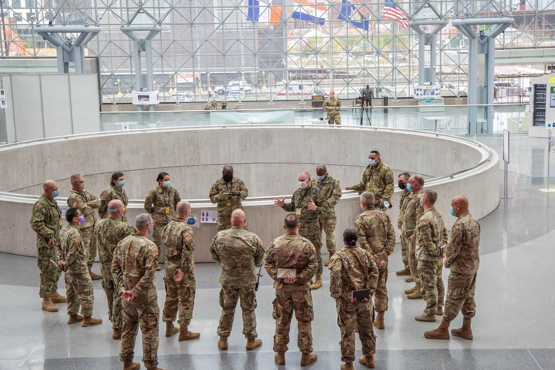 Uniformed personnel hold a socially distanced meeting.