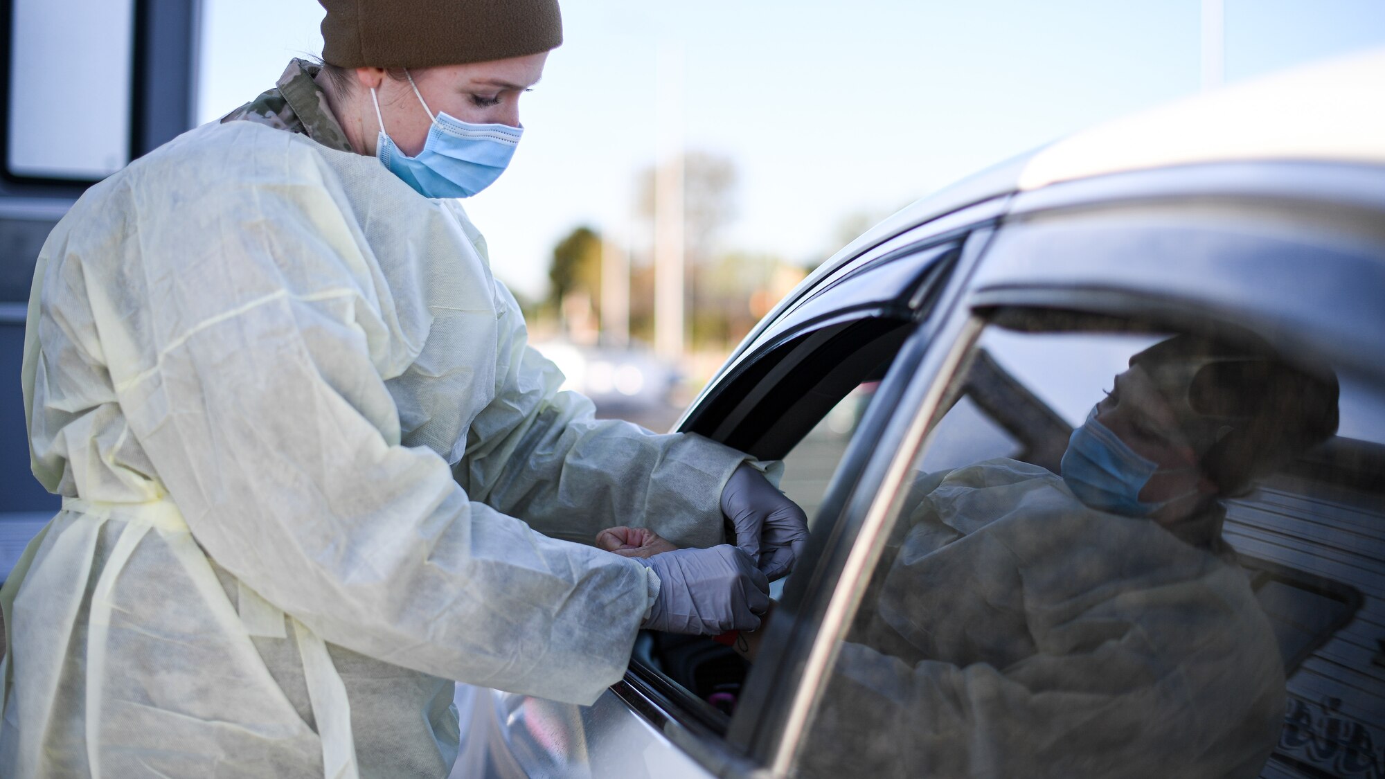 Senior Airman Amber Sansevieri, 75th Medical Group, puts a wristband on a visitor during a drive-thru COVID-19 screening.