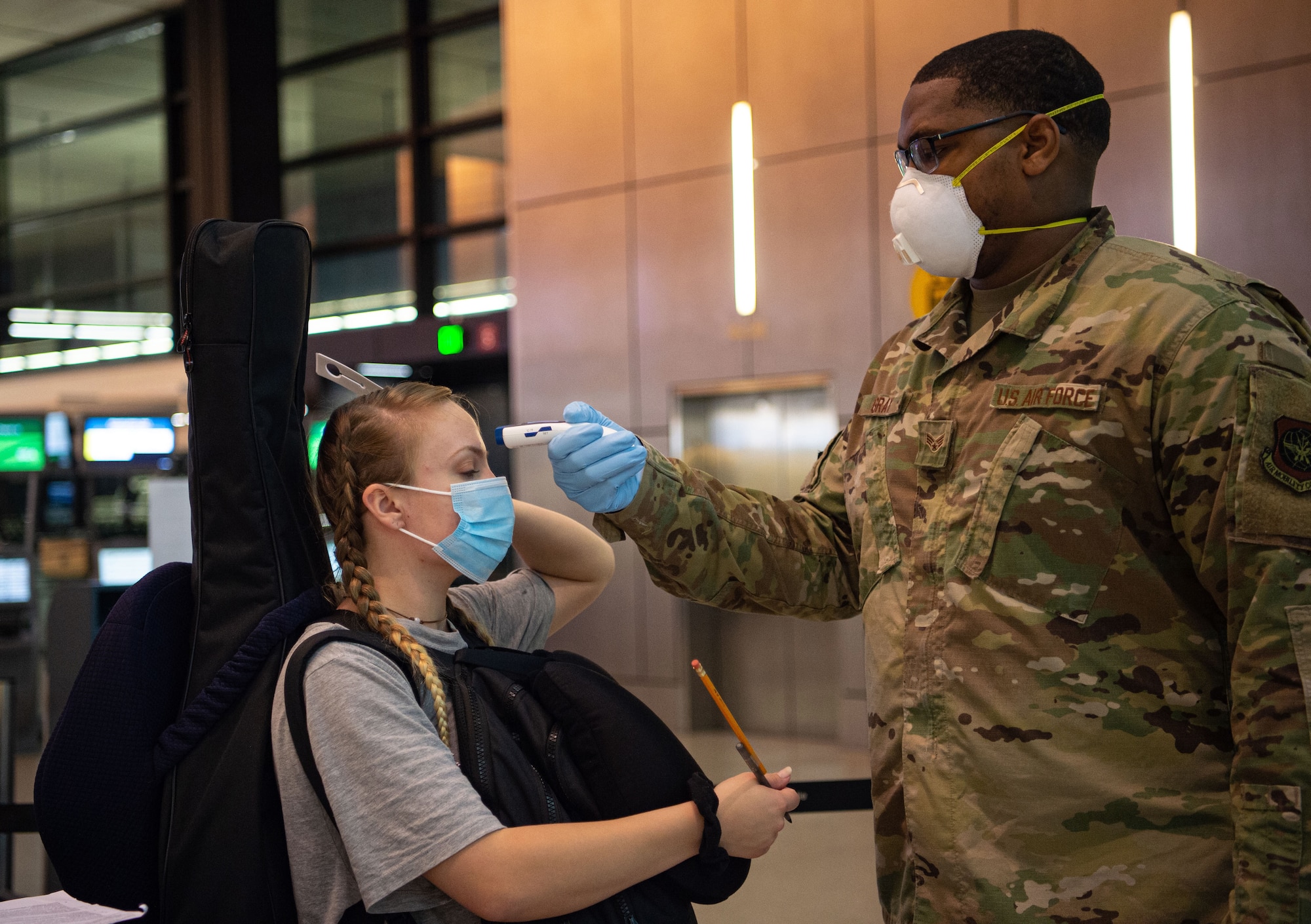 Senior Airman Kevin Gray II, 62nd Aerial Port Squadron passenger service specialist, takes the temperature of a passenger traveling to Asia at the Seattle-Tacoma International Airport in Seattle, Wash., April 30, 2020. Passengers with a fever of 100.4 degrees or higher are denied travel as a precaution against the spread of COVID-19. (U.S. Air Force photo by Senior Airman Tryphena Mayhugh)