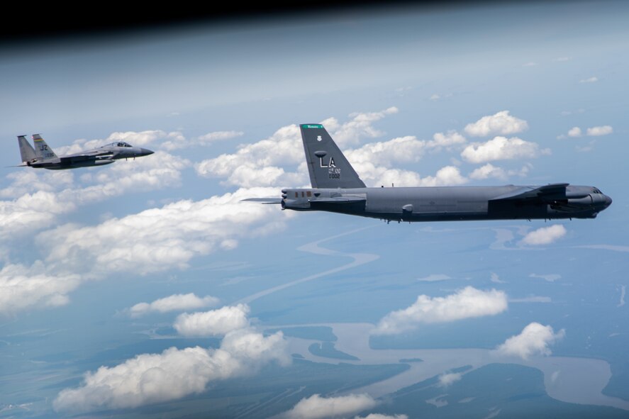 An F-15 Strike Eagle and B-52 Stratofortress fly over the Mississippi River