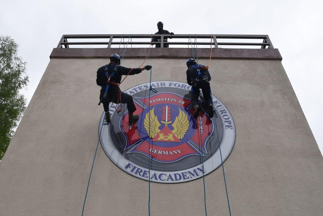 Airmen rappel down a wall.